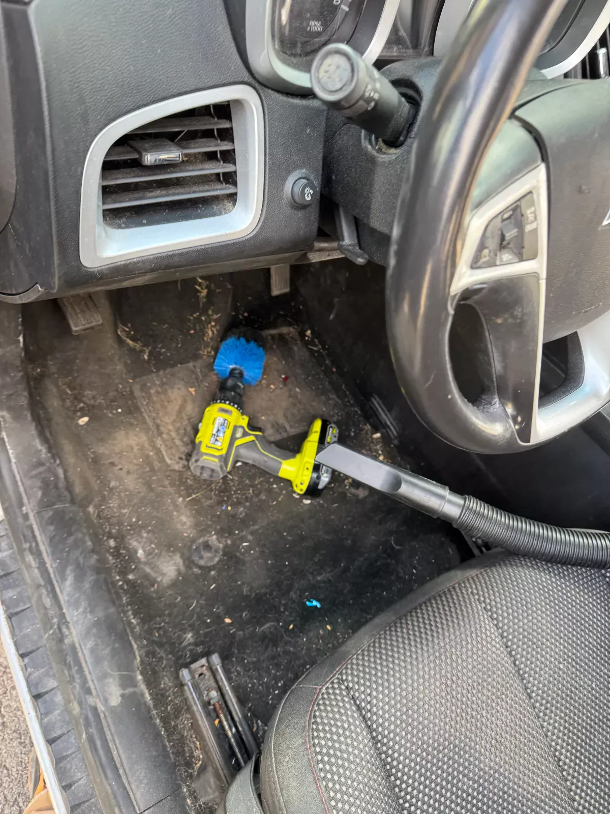 Driver side floor being scrubbed with a drill brush and vacuum during interior detailing by Buffalo Carpet NY